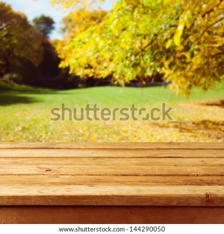Empty wooden table over autumn park background. Ready for product montage