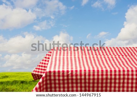 Empty table covered with red checked tablecloth over beautiful sky. Ready for product montage