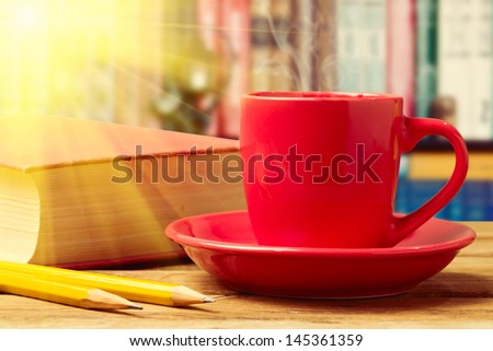 Red coffee cup with books and pencils