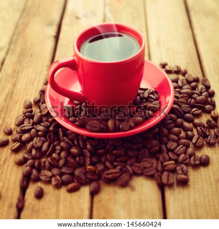 Red coffee cup with coffee beans on wooden background