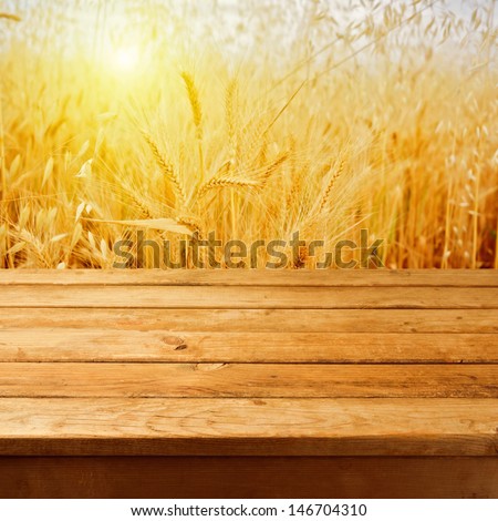 Empty wooden deck table over wheat field with sunset or sunrise. Ready for product montage