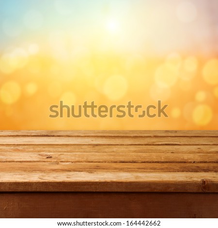 Empty wooden deck table over sunset bokeh background