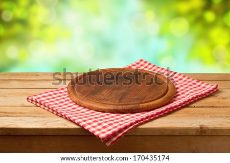 Round board on tablecloth on wooden table over bokeh background. Ready for product montage display