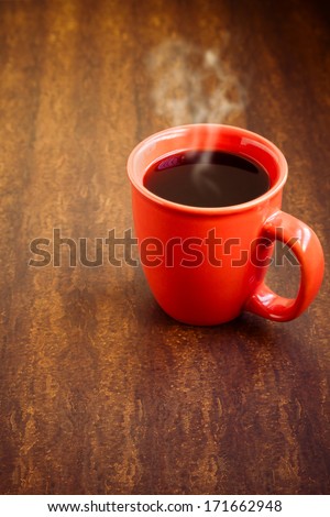 Cup with hot black coffee over wooden background