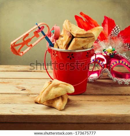 Hamantaschen cookies in bucket with grogger noise maker and carnival mask