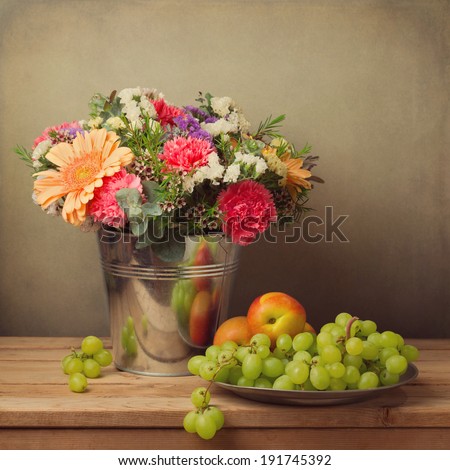 Flower bouquet in bucket  and fresh fruits on wooden table