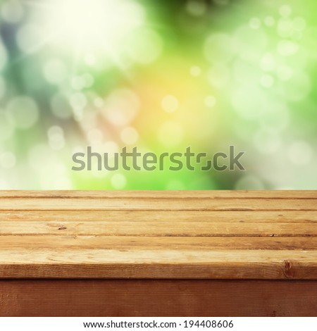 Empty wooden deck table with foliage bokeh background. Ready for product display montage.