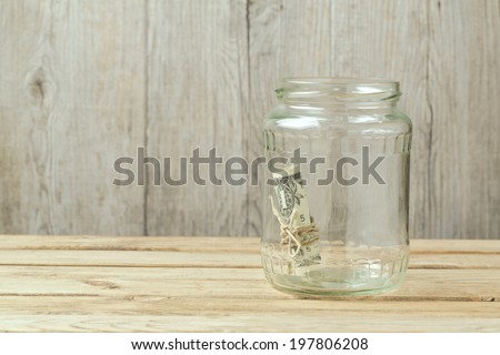 Money in glass jar on wooden table