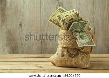 Money in sack on wooden table
