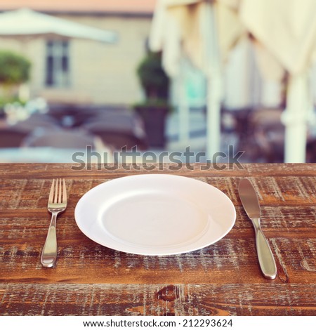 Restaurant background with empty plate and silverware
