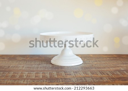 Cake plate on vintage wooden table over bokeh background