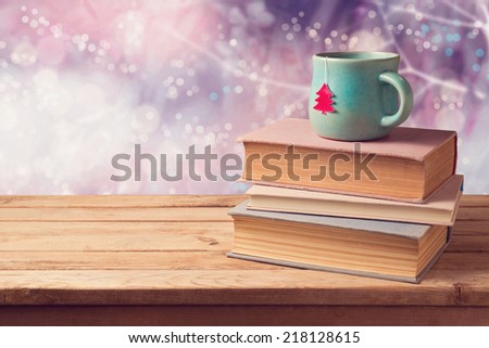 Christmas cup of tea and vintage books on wooden table over beautiful winter bokeh background with copy space