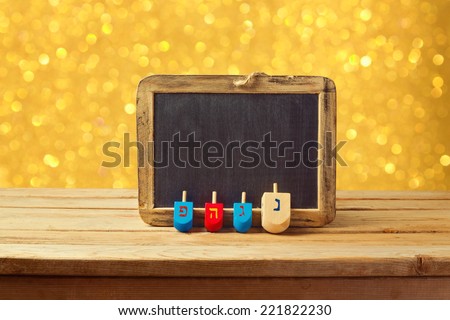 Jewish Holiday Hanukkah background with wooden dreidel spinning top and chalkboard over golden bokeh lights