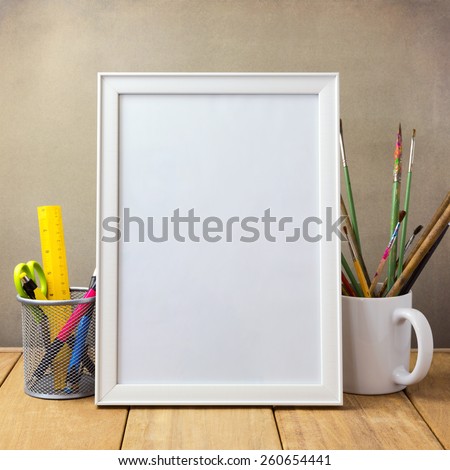 Poster mock up template with office items and painting brushes on wooden table