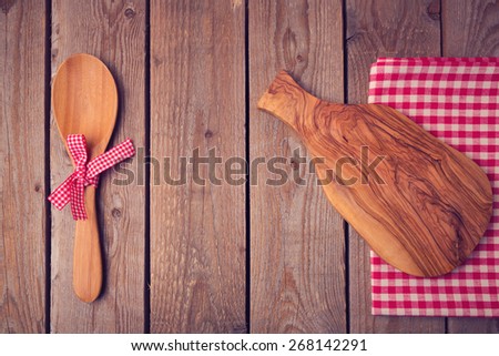 Cutting board and spoon on wooden table. View from above