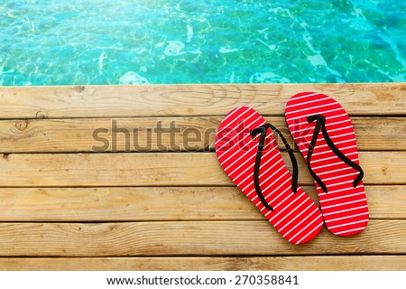 Flip flops on wooden deck over water background