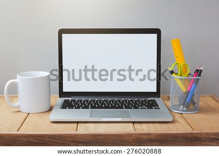 Laptop with white screen mock up template. Office desk with computer; coffee cup and pen