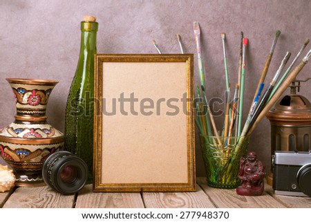 Mock up poster frame with vintage artistic objects and old camera on wooden table