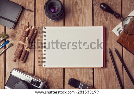 Notebook mock up for artwork or logo design presentation with film camera and lens. View from above