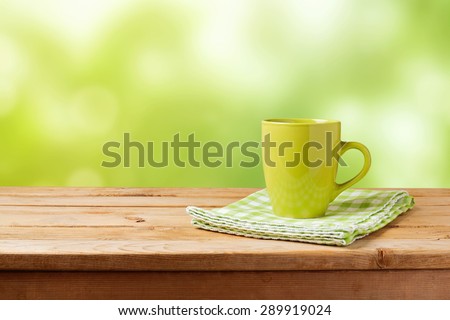 Coffee cup on wooden table over green bokeh background. Mock up for logo design display