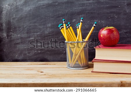 Back to school background with books, pencils and apple over chalkboard