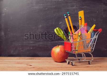 Shopping cart with school supplies over chalkboard background