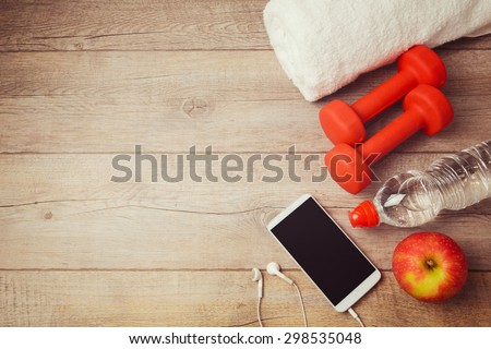 Fitness background with bottle of water, dumbbells and smartphone. View from above