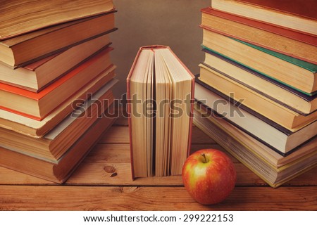 Vintage books with apple on wooden table. Reading a lot of books concept