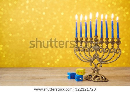 Jewish holiday Hanukkah background with vintage menorah and spinning top dreidel over lights bokeh. The Hebrew letters are the first letters of the words which means \