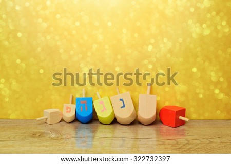 Jewish holiday Hanukkah background with spinning top dreidel over gold bokeh. Copy space for text. The Hebrew letters are the first letters of the words \