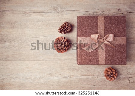 Christmas gift box with pine corn on wooden background. View from above