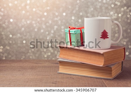 Christmas celebration with cup and gift box on books over bokeh background