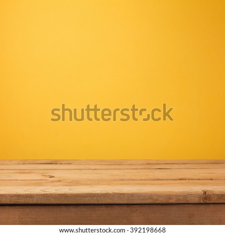 Empty wooden deck table over yellow wallpaper background