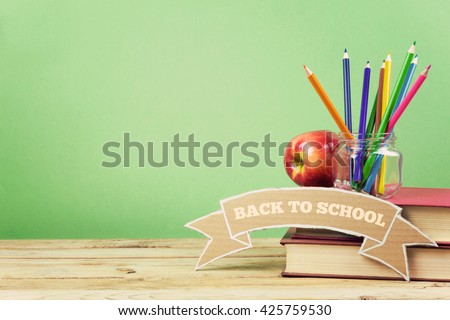 Back to school background with books, pencils and apple on wooden table.