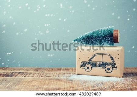 Christmas holiday gift box with car drawing and pine tree on wooden table