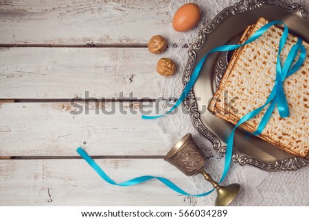 Jewish holiday Passover concept with matzah, seder plate and wine glass on white table background. View from above. Flat lay