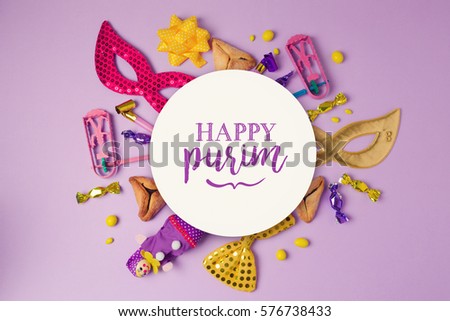 Purim holiday concept with white paper circle and party supplies on purple background. Top view from above