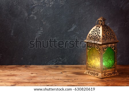 Lightened lantern on wooden table over dark background. Ramadan kareem holiday celebration concept