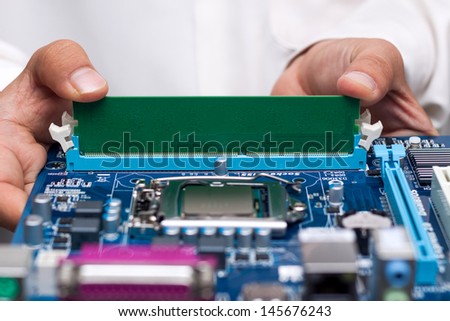 Technician's hands installing user memory on a computer main-board