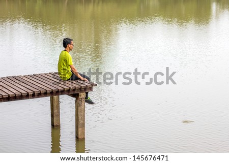 man sitting on a wooden pier