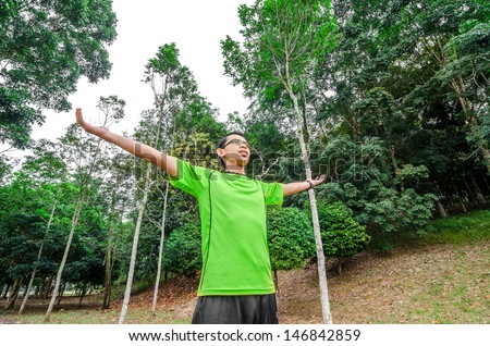 Enjoying the nature. Young man arms raised enjoying the fresh air in green forest.
