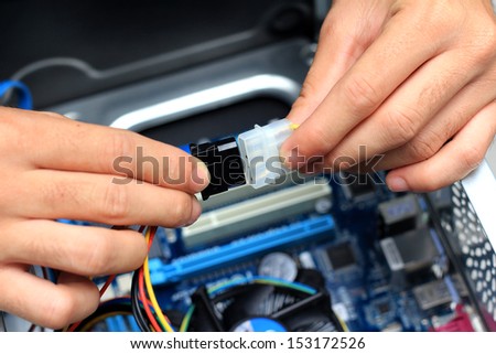 Closeup of a technician\'s hands wiring a computer mainboard