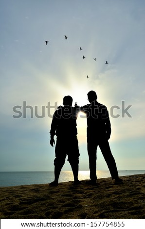 silhouette of two friends near the beach