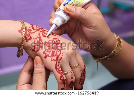 human hand being decorated with henna tattoo