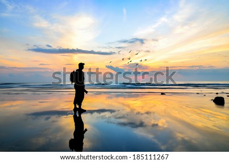 Silhouette of a photographer looking to the birds flying when sun rising up