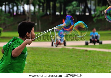 PAHANG, MALAYSIA - MARCH 29, 2014 : Kids playing with giant bubble at Putrajaya Hot Balloon Fiesta 2014 located at Putrajaya, Malaysia.