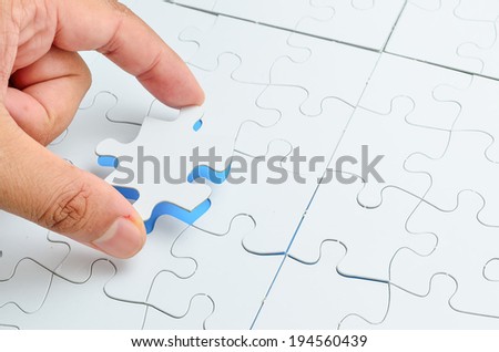 Person fitting the last puzzle piece.Concept image of building and button up