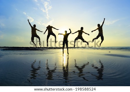 Silhouette of friends jumping over sun rising up