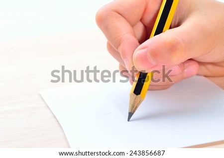 Pencil in hand writing on paper