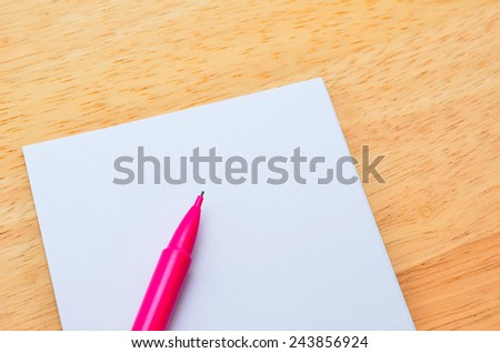 Blank post-it with pen on office wooden table. Above view
